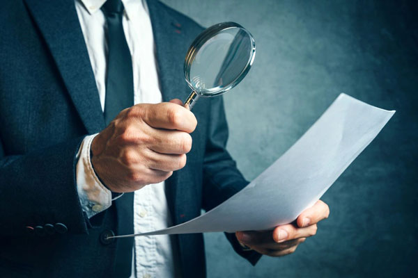 How do you choose an accountant - man with magnifying glass looking at letter of engagement.